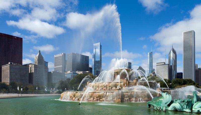 Buckingham Fountain in Grant Park with the Chicago skyline under a blue sky.